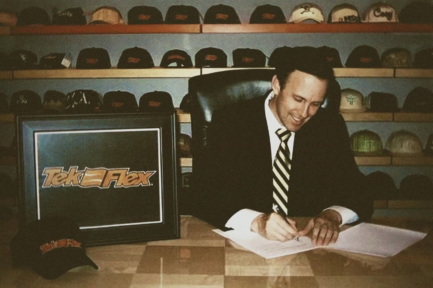 Putnam's founder signing an early licensing deal, framed by a wall of caps.